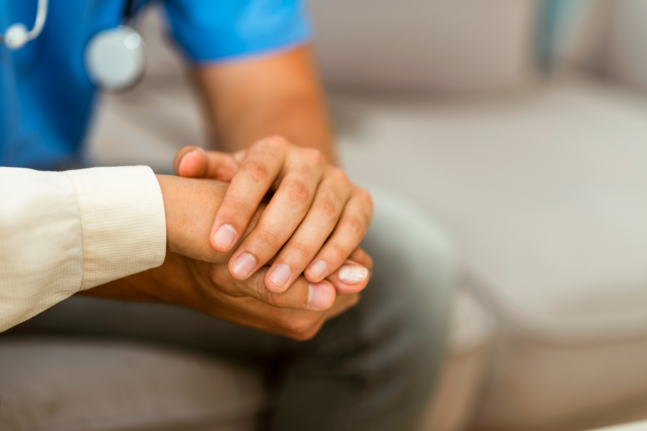 A doctor holds a patient's hand. 